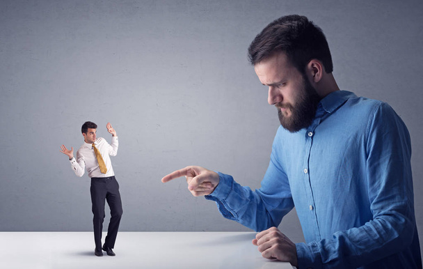 Young businessman fighting with miniature businessman - Photo, Image