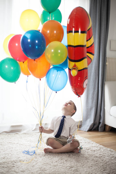 Nelivuotiaan pojan muotokuva, jolla on ilmapalloja. Syntymäpäivä. Onnellinen lapsi puvussa. Rakkaus
. - Valokuva, kuva