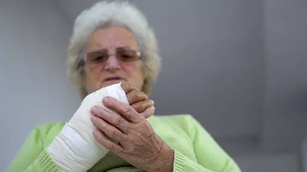 Old woman massage her broken hand outdoors - Fotó, kép