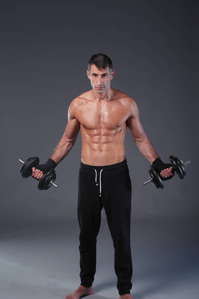 Handsome muscular man working out with dumbbells. Personal fitness instructor. Personal training. - Foto, immagini