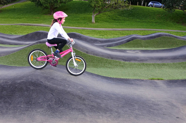 Nuori tyttö (ikä 08) ratsastaa polkupyörän este trek julkisessa puistossa
. - Valokuva, kuva