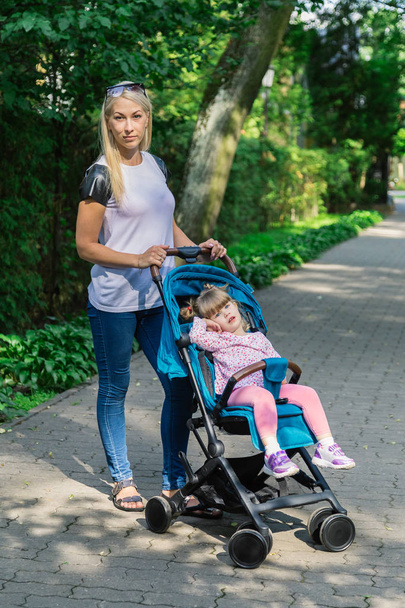 Mother walking while pushing a stroller in the park - Photo, Image