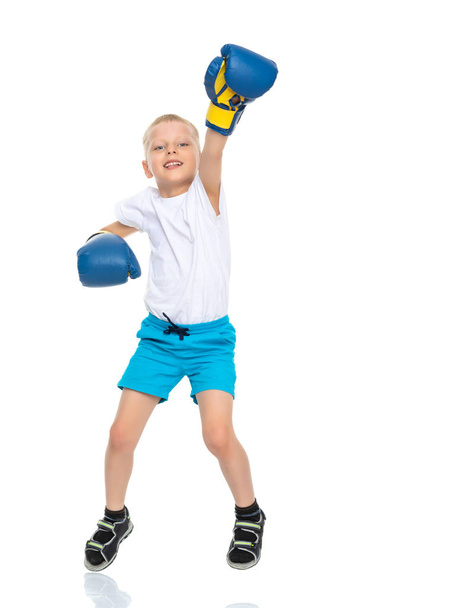 A little boy in a clean white T-shirt and boxing gloves. - 写真・画像