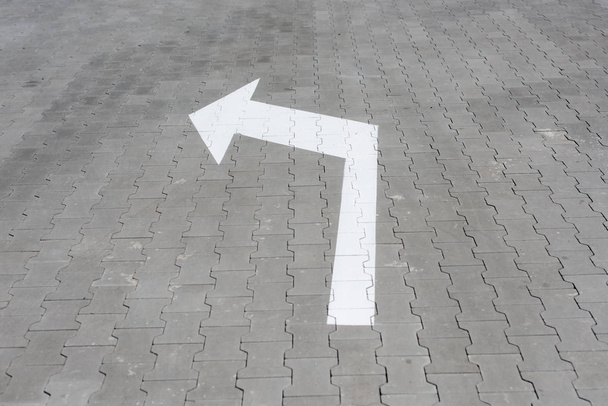 White arrow down on street tile. Sign for pedestrians show the way left - Photo, Image