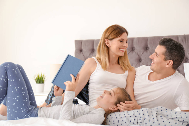 Happy family reading book with child in bedroom - Zdjęcie, obraz
