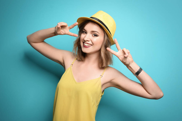 Beautiful young woman with stylish hat posing on color background - Фото, зображення