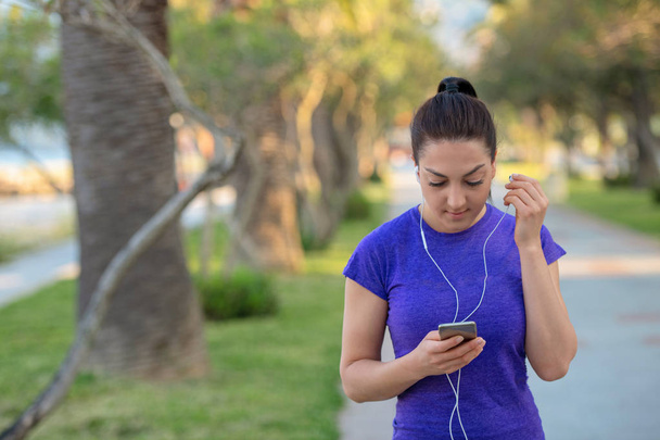 closeup portrait of young female runner in blue t-shirt  listening to music on earphones  - Фото, изображение