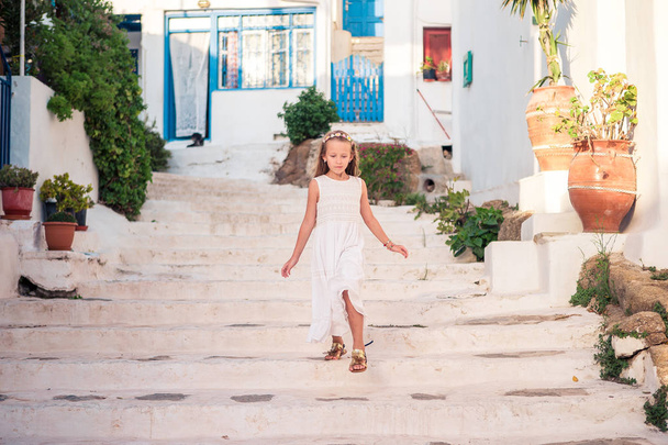 Kid at street of typical greek traditional village with white walls and colorful doors on Mykonos Island - Photo, Image