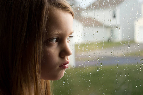 Menina triste olhando para fora janela chuvosa
 - Foto, Imagem
