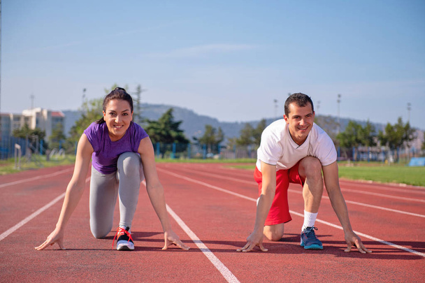 Jong sportief stel aan begin voordat joggen op de atletiekbaan  - Foto, afbeelding