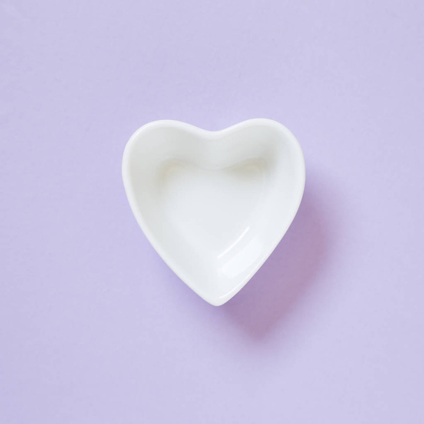Heart shaped white dish isolated on purple background - Foto, Bild