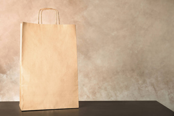 Mockup of paper shopping bag on table against color background - Foto, afbeelding
