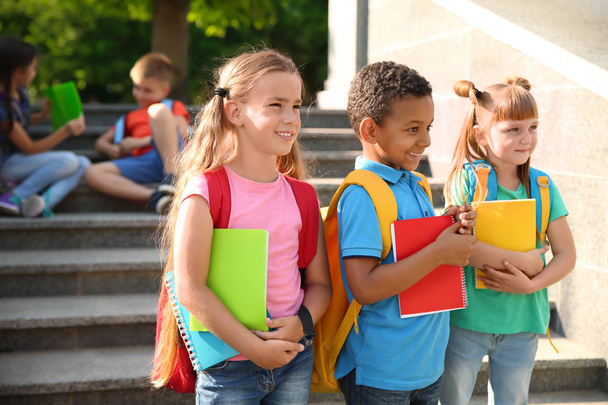 Leuke lieve kinderen met rugzakken en notebooks outdoors. Basisschool - Foto, afbeelding