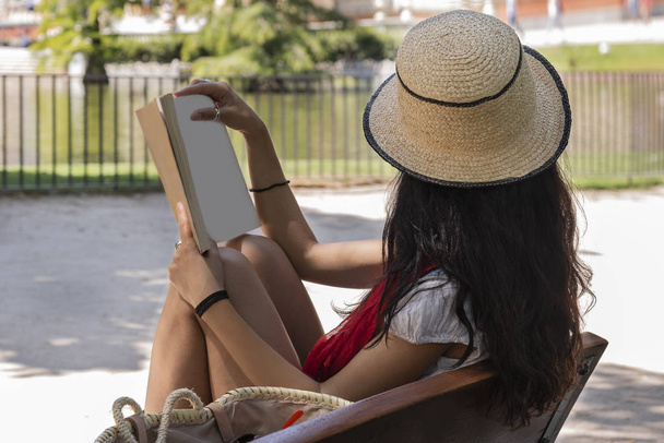 eautiful 若い女性が公園のベンチに座って本を読みます。リラックスした概念 - 写真・画像