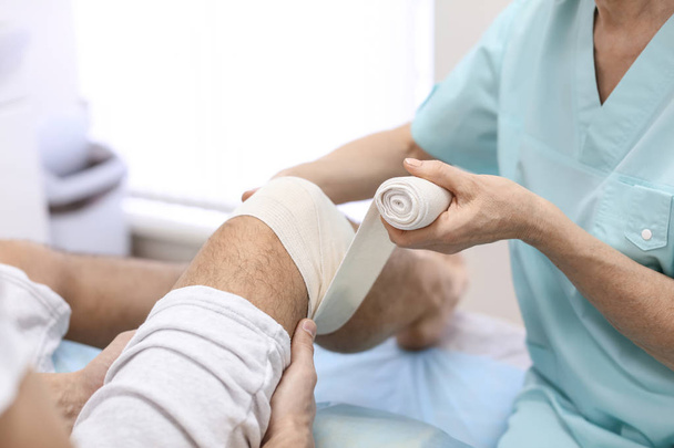 Orthopäde bandagiert Patient Bein im Krankenhaus - Foto, Bild
