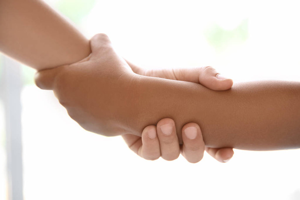 Children holding hands on light background, closeup. Unity concept - Photo, Image