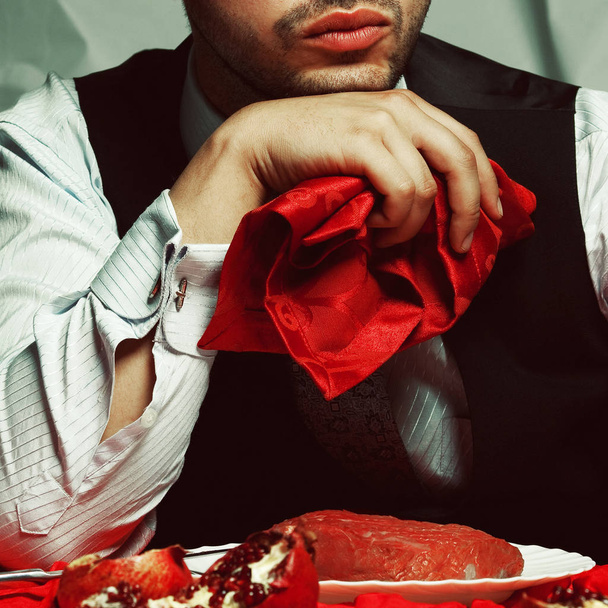 Baroque supper of blue blood aristocrat. Portrait of satisfied handsome man eating fresh meat at the vintage restaurant. Classic vest & shirt. Bristle on face. Luxury retro style. Closeup. Indoor shot - Foto, Imagen