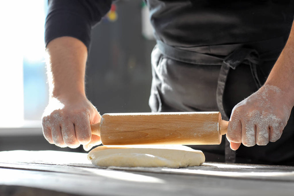 Бейкер прокатки тісто на кухонному столі - Фото, зображення