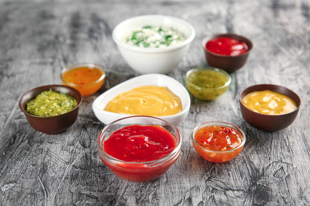 Cuencos con diferentes salsas sobre fondo texturizado gris
 - Foto, imagen