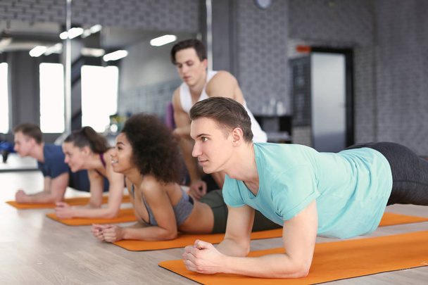 Sporty young people doing exercise in gym - Photo, Image