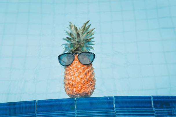 Piña con gafas de sol en la piscina., concepto de verano y vacaciones
. - Foto, Imagen