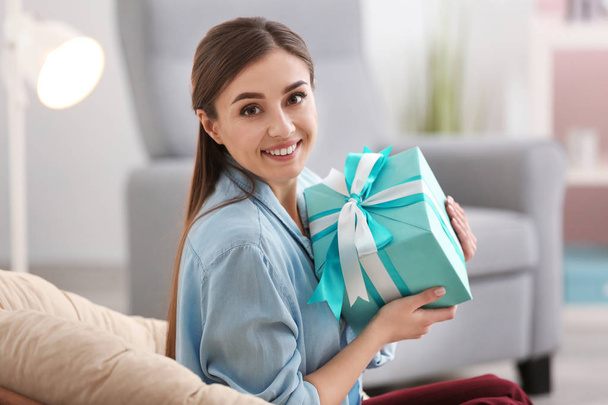 Beautiful young woman with gift box at home - Фото, зображення