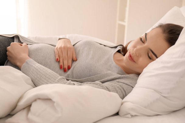 Ochtend van mooie zwangere vrouw liggend op bed - Foto, afbeelding