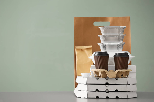 Різні пакети і картонні чашки на столі на кольоровому фоні. Служба доставки їжі
 - Фото, зображення