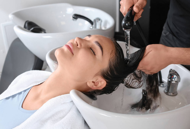 Молодая женщина во время мытья волос в салоне красоты
 - Фото, изображение