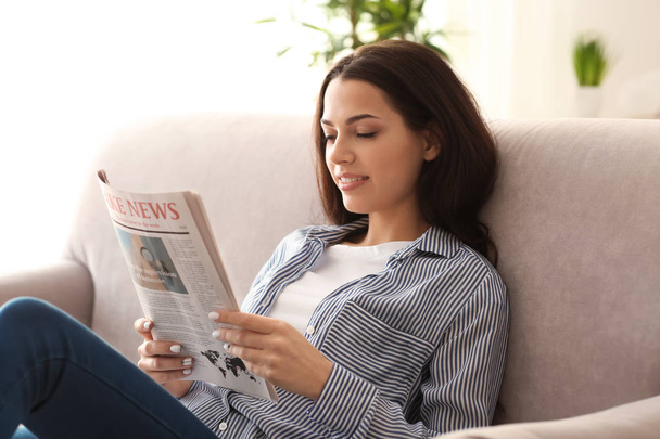 Young woman reading newspaper indoors - Foto, immagini