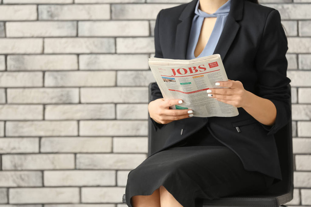 junge Geschäftsfrau liest Zeitung vor Backstein-Hintergrund - Foto, Bild
