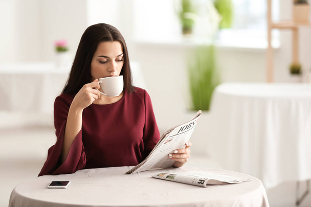 Młoda kobieta czytanie gazety podczas picia kawy w kawiarni - Zdjęcie, obraz