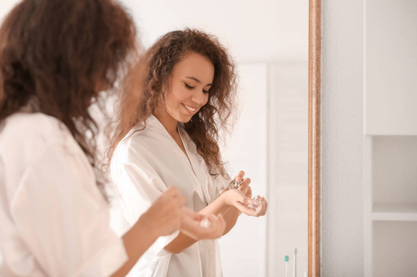 Manhã da jovem afro-americana aplicando perfume em casa
 - Foto, Imagem