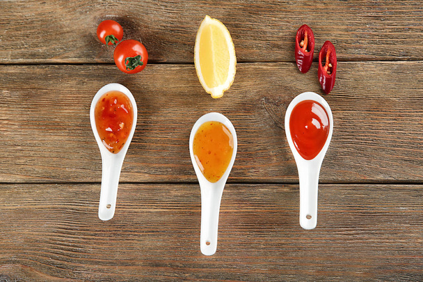 Flat lay composition with different sauces and ingredients on wooden background - Photo, Image