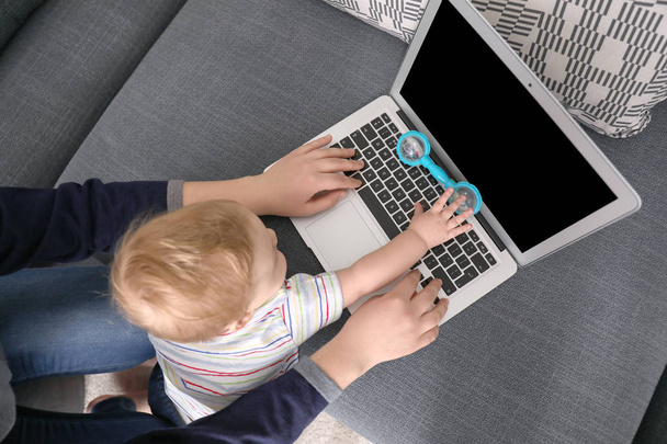 Молода мати з дитиною використовує ноутбук вдома, вид зверху
 - Фото, зображення