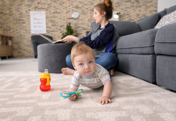 Little baby crawling on carpet while mother working at home - Photo, Image