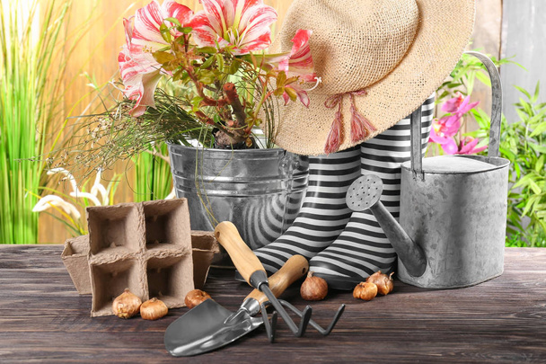 Équipement de jardinage avec des bottes de gomme sur table en bois
 - Photo, image