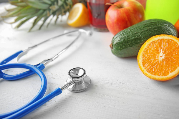 Stethoscope with fresh healthy food on white table - Фото, зображення