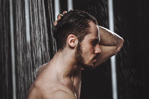 Close-up side view photo of a young man taking a shower - 写真・画像