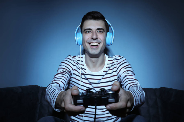 Jovem jogando videogame em casa à noite
 - Foto, Imagem