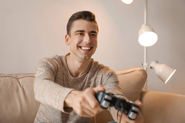 Jeune homme jouant à un jeu vidéo à la maison - Photo, image