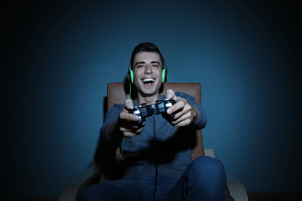 Νεαρός παίζει βίντεο παιχνίδι στο σπίτι το βράδυ - Φωτογραφία, εικόνα