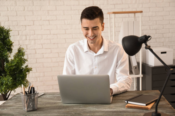 Молодой бизнесмен использует ноутбук в офисе
 - Фото, изображение