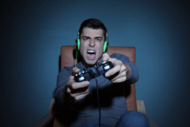 Молодой человек играет в видеоигры дома вечером
 - Фото, изображение