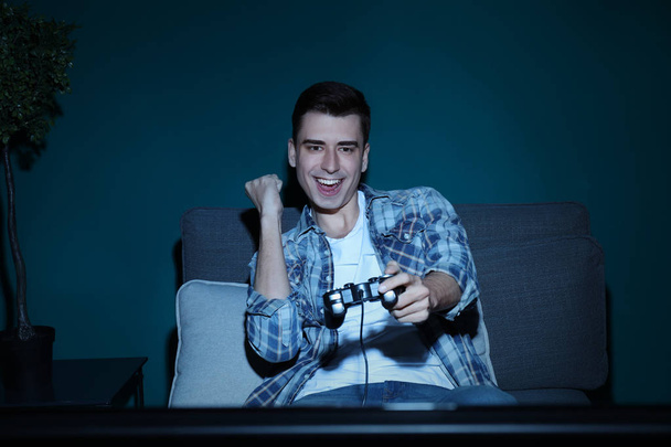 Νεαρός παίζει βίντεο παιχνίδι στο σπίτι το βράδυ - Φωτογραφία, εικόνα