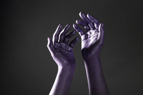 Female hands dyed in purple color on dark background - Foto, imagen
