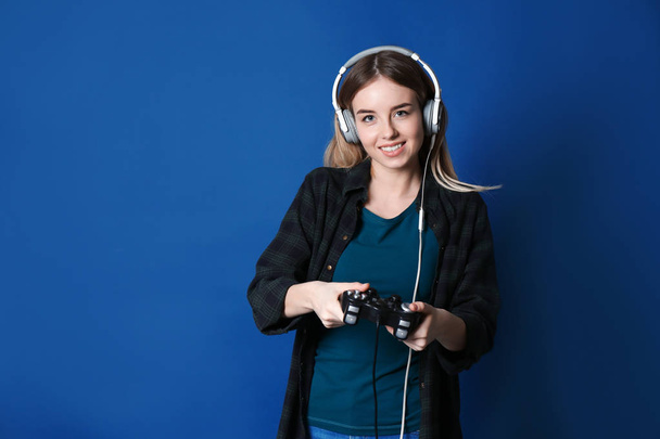 Jonge vrouw met gamepad op kleur achtergrond - Foto, afbeelding