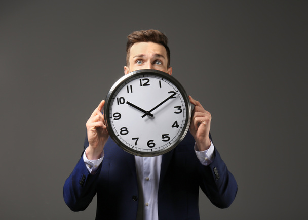 Successful businessman with clock on dark background. Time management concept - Foto, Imagen