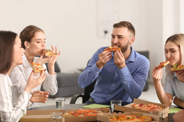 Les jeunes mangent des pizzas à table au bureau
 - Photo, image