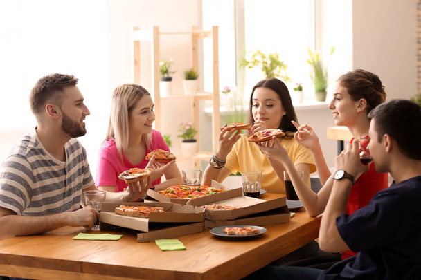 Sisätiloissa pizzaa syövät nuoret
 - Valokuva, kuva